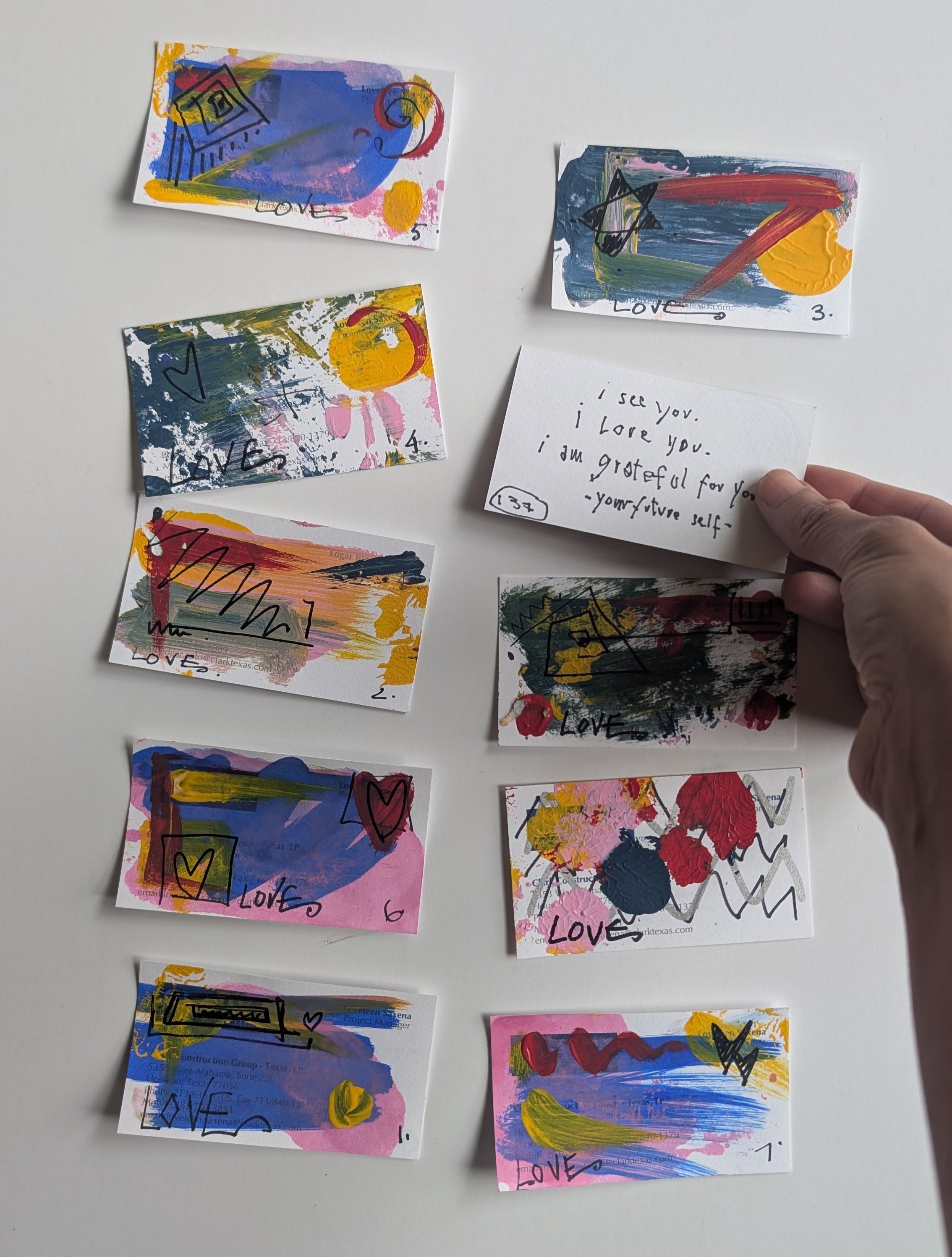Colorful hand-drawn cards with 'love' messages on a gray surface.