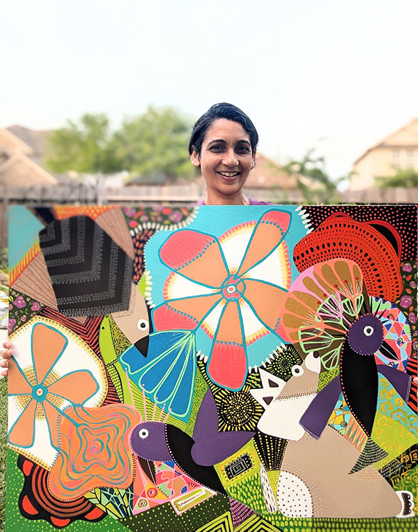 Woman holding a colorful abstract art piece with animals and geometric shapes.