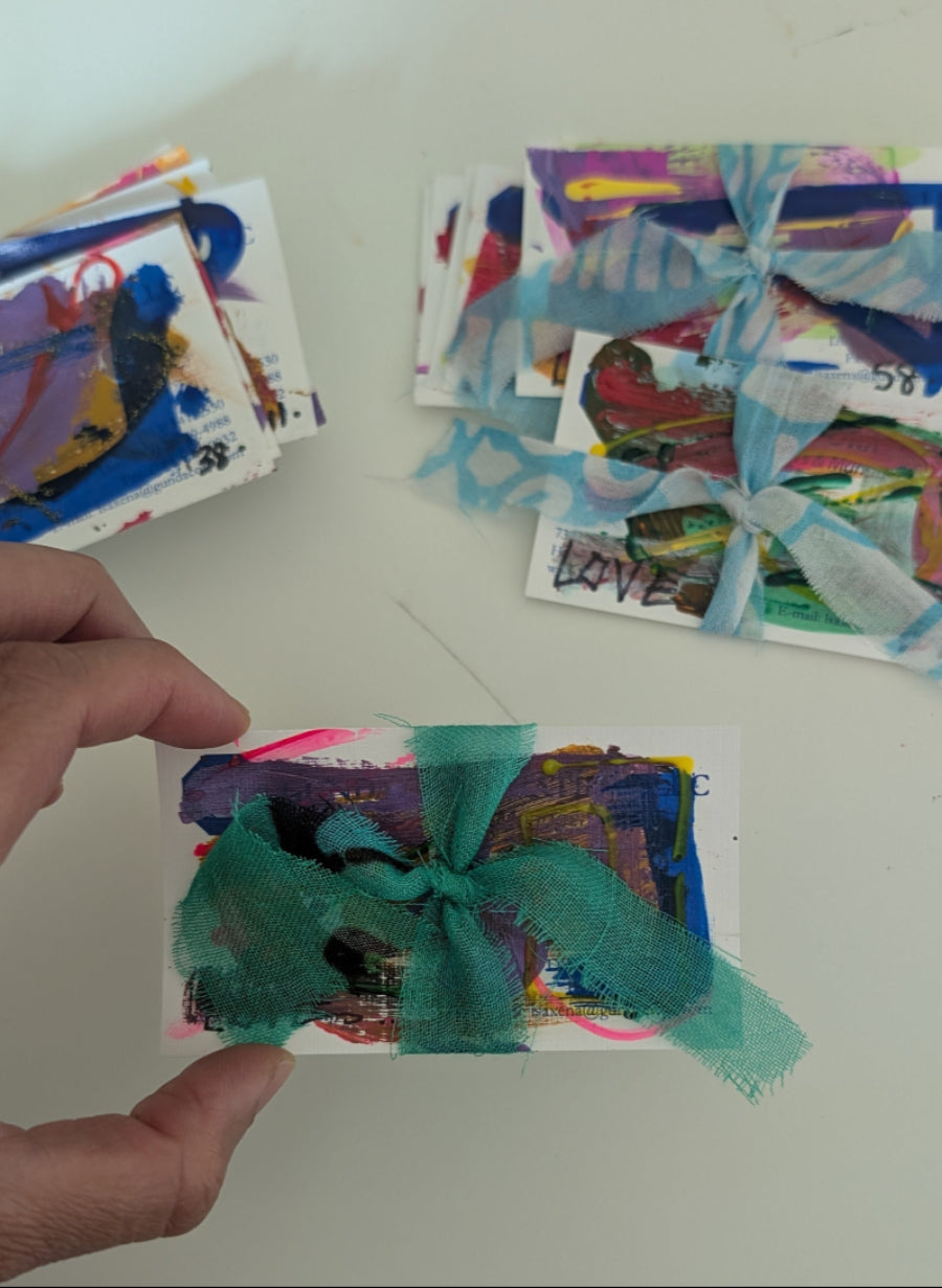 Colorful card with a green bow held by a hand on a white surface